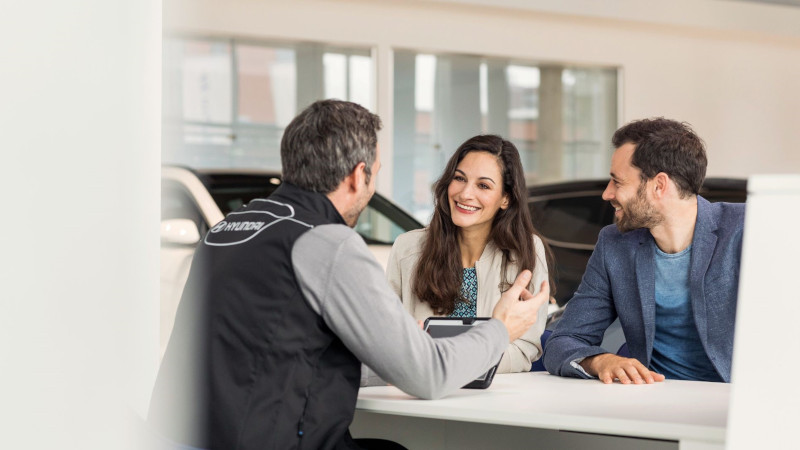 zaměstnanec hyundai ukazuje výhodné nabídky pojištění páru